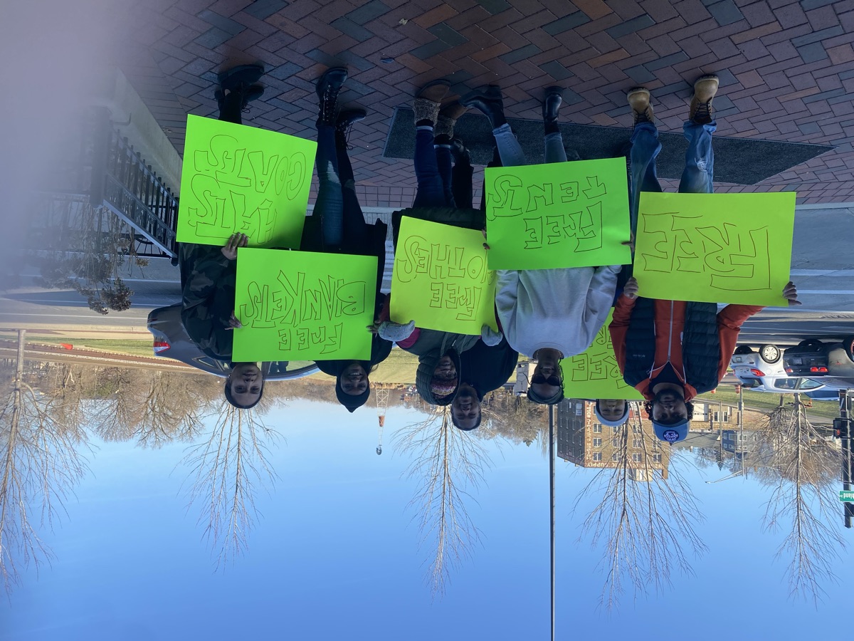 Volunteers holding signs — Free Tents, Free Clothes, Free Blankets